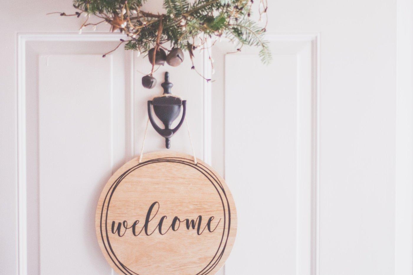 Rond houten bordje met welcome aan een witte voordeur