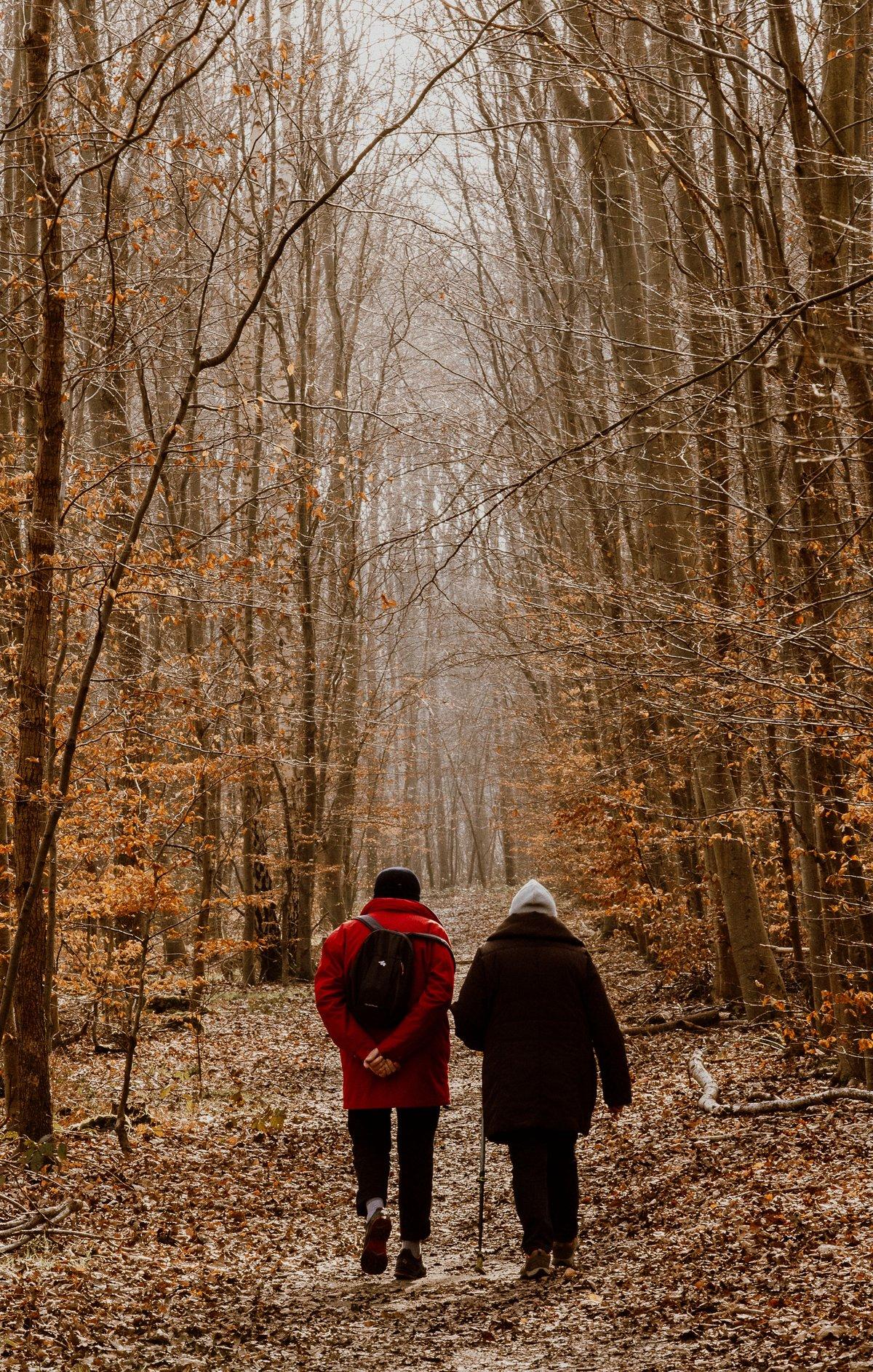Twee mensen wandelen samen over een rustig pad tussen herfstbladeren