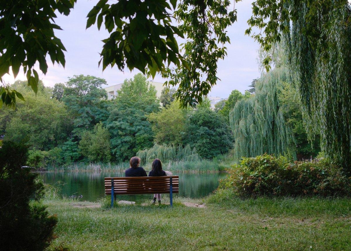 Twee mensen zitten samen op een bankje aan het water in het park
